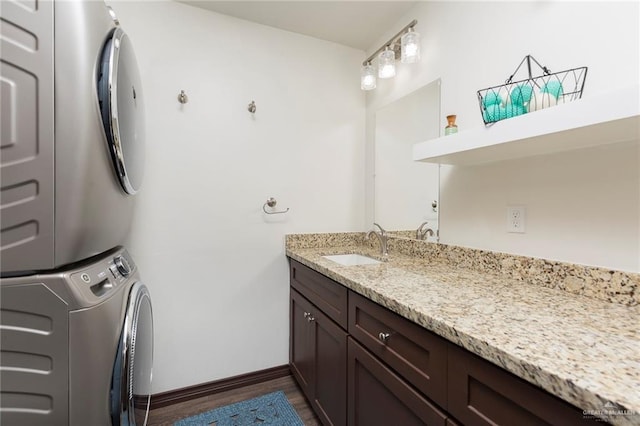 clothes washing area featuring stacked washer / dryer, sink, and dark hardwood / wood-style floors