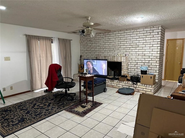 living room with ceiling fan, a brick fireplace, a textured ceiling, and light tile patterned flooring