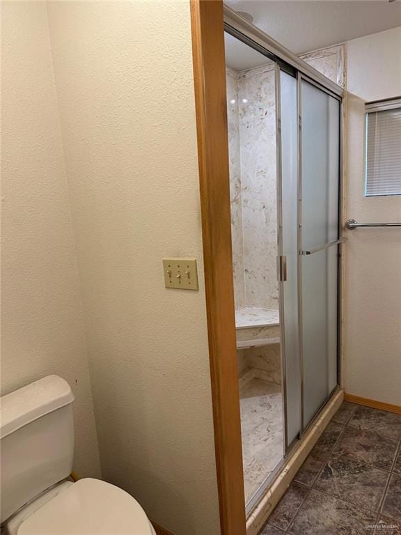 bathroom with a shower with shower door and toilet