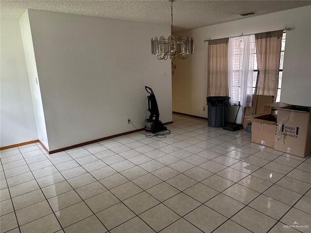 unfurnished dining area with an inviting chandelier, a textured ceiling, and light tile patterned floors