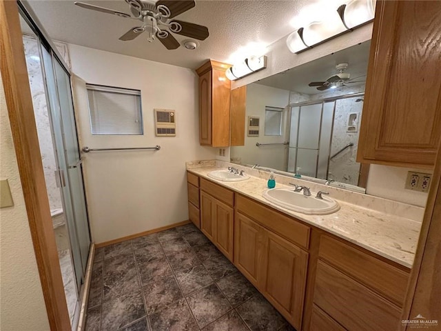 bathroom featuring a shower with door, vanity, ceiling fan, and a textured ceiling