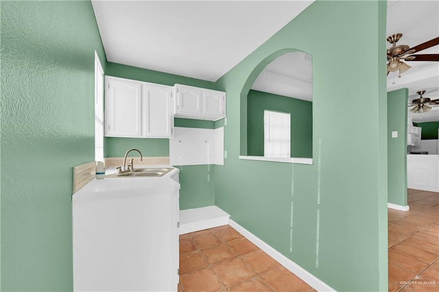 washroom featuring laundry area, light tile patterned floors, baseboards, and a sink