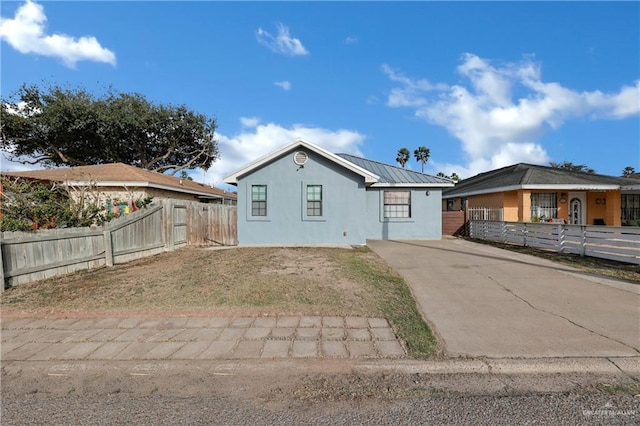 view of front of home with a fenced front yard, metal roof, and stucco siding