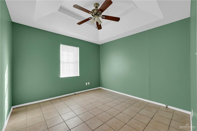 spare room with ceiling fan, a tray ceiling, light tile patterned floors, and baseboards