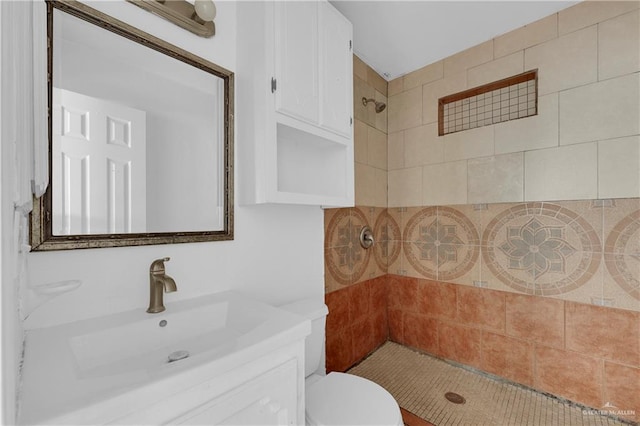 full bathroom with a tile shower, vanity, and toilet