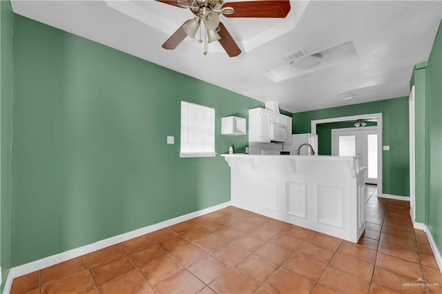 kitchen with baseboards, visible vents, a peninsula, light countertops, and white cabinetry