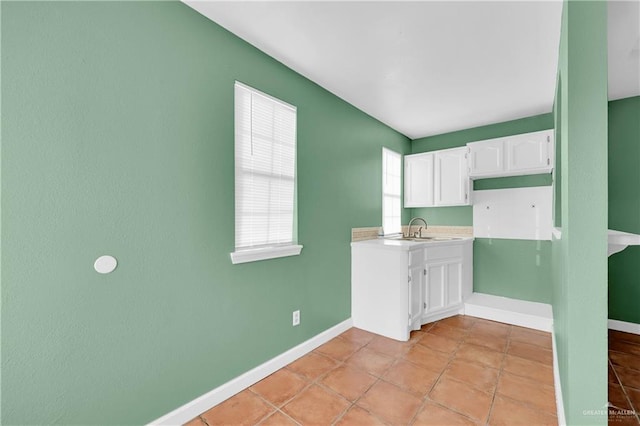 washroom featuring light tile patterned flooring, a sink, and baseboards