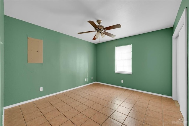 spare room featuring a ceiling fan, electric panel, baseboards, and light tile patterned floors