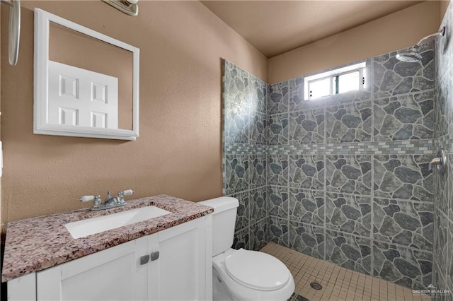 full bath featuring toilet, a textured wall, a shower stall, and vanity