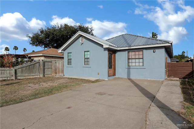 rear view of house featuring a patio area, fence, metal roof, and stucco siding