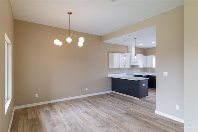 kitchen with white cabinets, light hardwood / wood-style floors, hanging light fixtures, and a chandelier