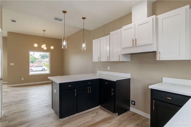 kitchen with kitchen peninsula, light wood-type flooring, decorative light fixtures, a notable chandelier, and white cabinetry