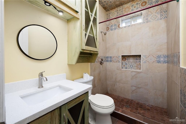 bathroom featuring vanity, toilet, and a tile shower