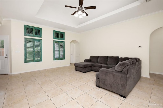 living room with ceiling fan, light tile patterned floors, ornamental molding, and a tray ceiling