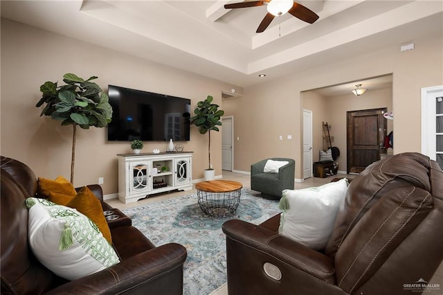 living room with a tray ceiling and ceiling fan