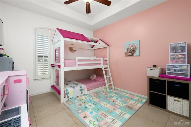 bedroom with a raised ceiling, light tile patterned floors, and ceiling fan