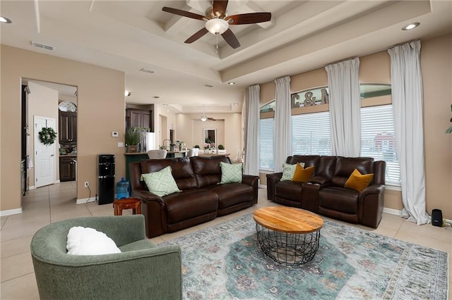 living room with a tray ceiling, ceiling fan, and light tile patterned flooring