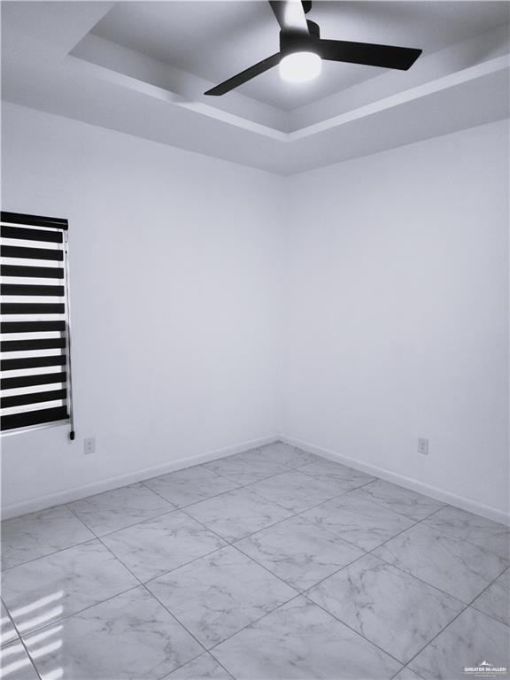 unfurnished room featuring a raised ceiling and ceiling fan