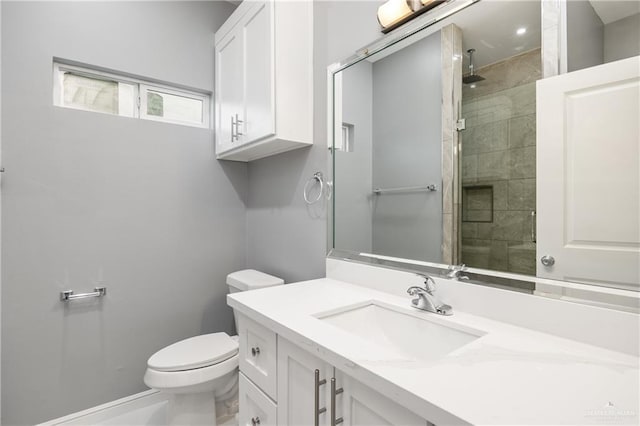 bathroom featuring vanity, a shower with door, and toilet