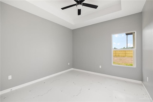 empty room featuring a raised ceiling and ceiling fan