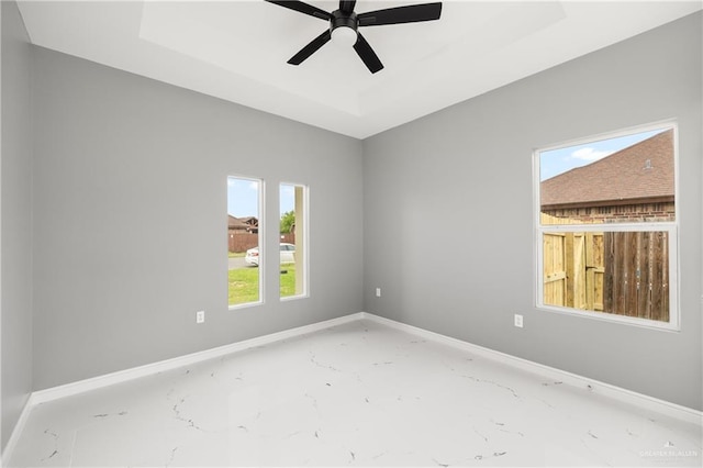 spare room with a raised ceiling and ceiling fan