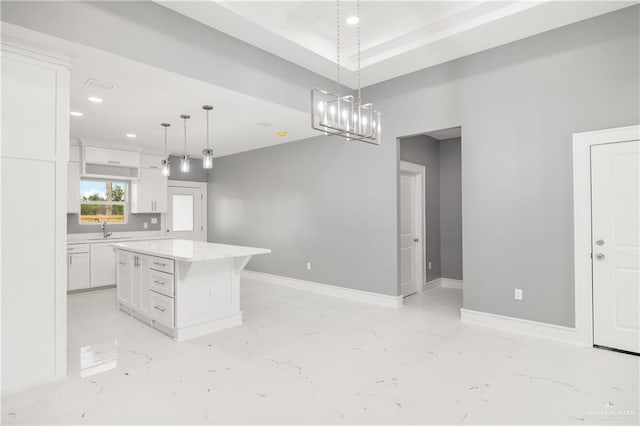 kitchen featuring white cabinetry, pendant lighting, a center island, and sink