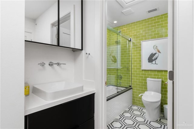 5705 Laguna Cir S, South Padre Island, TX 78597 - bathroom with tile patterned floors, tile walls, bath / shower combo with glass door, toilet, and visible vents