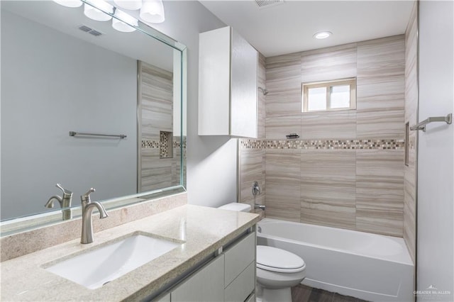 full bathroom with vanity, tiled shower / bath, and toilet