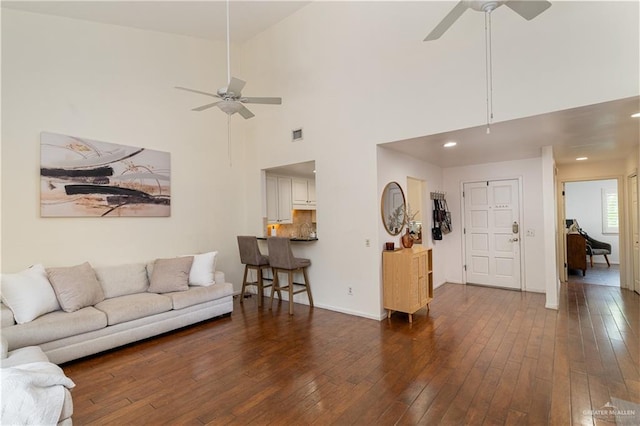 living area with visible vents, dark wood-style flooring, a ceiling fan, and baseboards