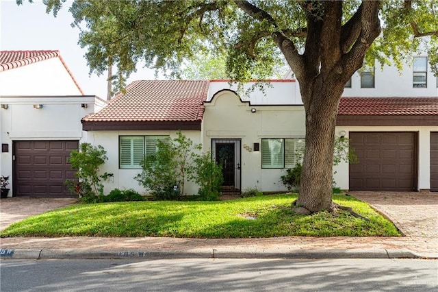 view of front of property with a garage, driveway, a tiled roof, and stucco siding