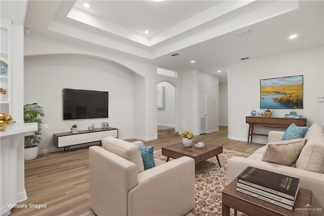 living room featuring a raised ceiling and light hardwood / wood-style floors