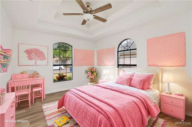 bedroom featuring a raised ceiling, ceiling fan, and hardwood / wood-style floors