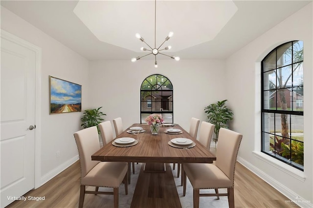 dining area with hardwood / wood-style flooring, plenty of natural light, and a chandelier