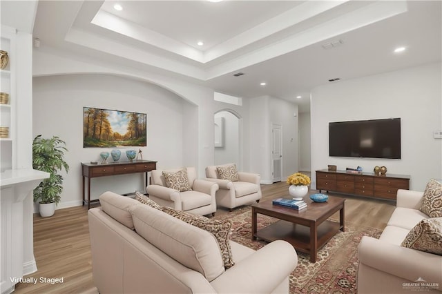 living room with a tray ceiling and light hardwood / wood-style floors