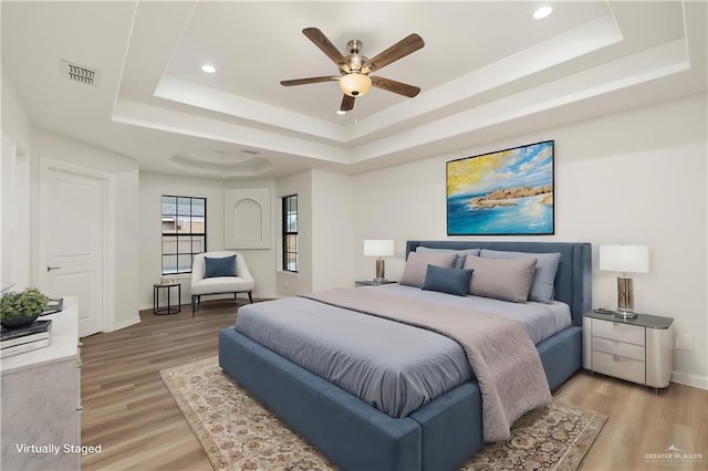 bedroom featuring hardwood / wood-style flooring, a tray ceiling, and ceiling fan