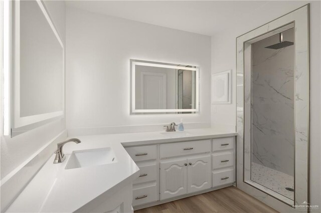 bathroom featuring hardwood / wood-style flooring, tiled shower, and vanity