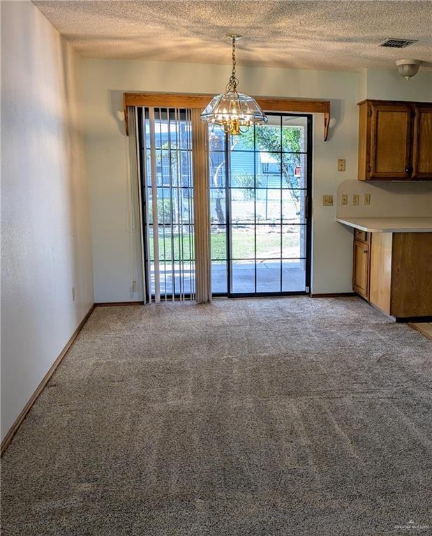 109 Green Gate Cir N, Palmview, TX 78572 - unfurnished dining area with plenty of natural light, light colored carpet, a textured ceiling, and a chandelier