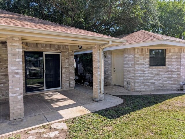 109 Green Gate Cir N, Palmview, TX 78572 - view of exterior entry with roof with shingles, a patio, and brick siding