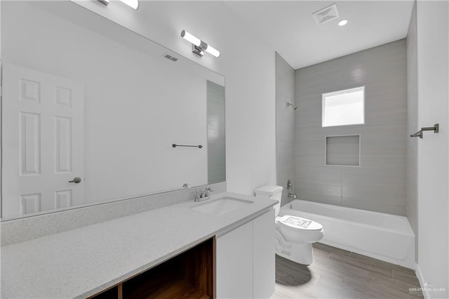 full bathroom with vanity, tiled shower / bath combo, and toilet