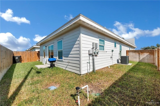 view of side of home with cooling unit and a yard