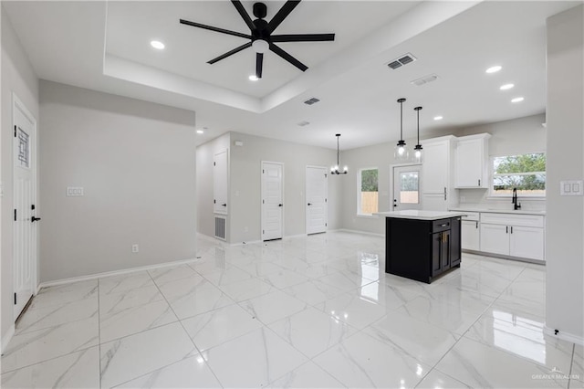 kitchen featuring plenty of natural light, white cabinetry, a center island, and decorative light fixtures