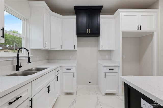 kitchen featuring white cabinets, light stone countertops, and sink