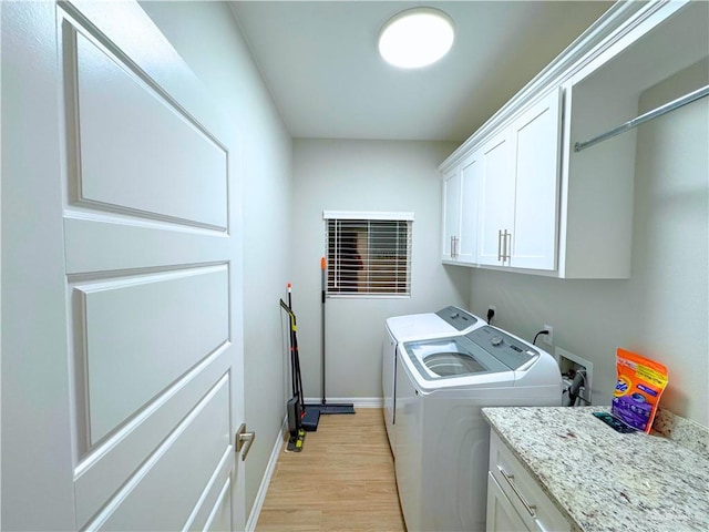 clothes washing area featuring washer and clothes dryer, cabinets, and light hardwood / wood-style flooring