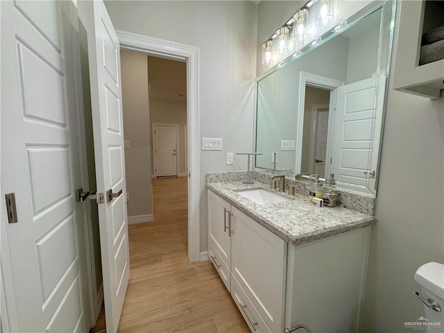 bathroom with wood-type flooring, vanity, and toilet