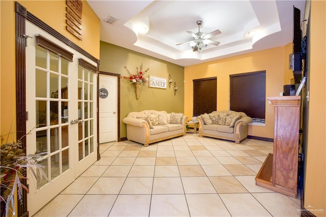 living room with light tile patterned floors, french doors, a tray ceiling, and ceiling fan