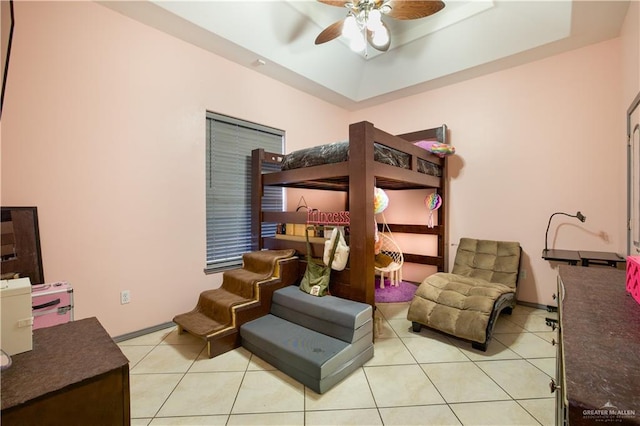 tiled bedroom with a tray ceiling and ceiling fan