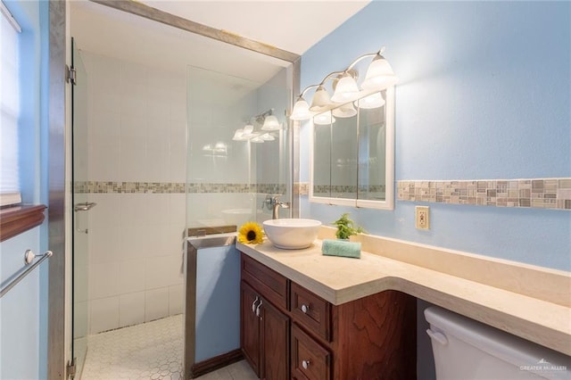 bathroom with toilet, tiled shower, and vanity