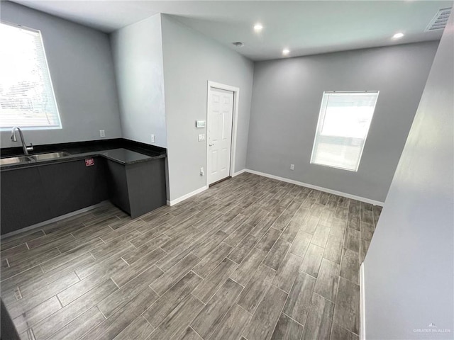 interior space with recessed lighting, wood finish floors, a sink, visible vents, and baseboards