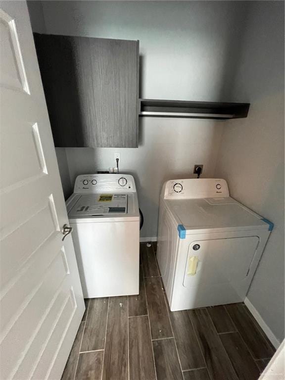 washroom featuring laundry area, baseboards, washer and clothes dryer, and wood finish floors