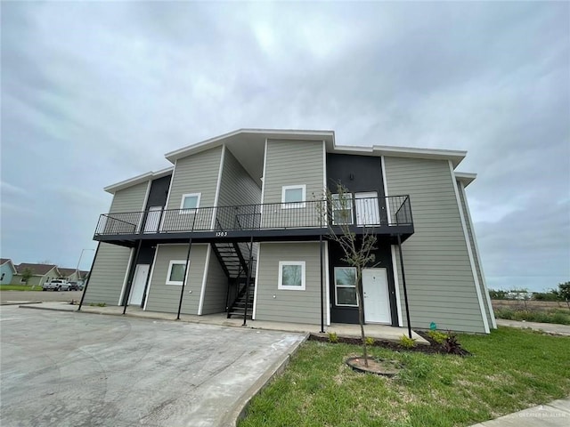 view of front of property featuring stairs, a front lawn, and a deck